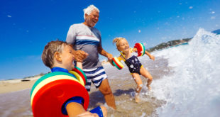 A senior man spends time with his grandchildren at the beach
