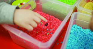 Children play educational games with a sensory bin in kindergarten