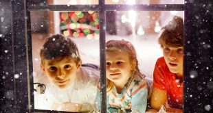 Three cute children sitting by window on Christmas eve. Two school kid boys and toddler girl, siblings looking outdoor and dreaming. Family happiness on traditional holiday.