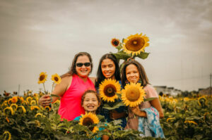 A family stands together in a field of sunflowers. 