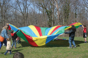 Kids playing with a multicolored tarp outdoors