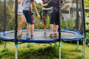 Four young children jump on a blue trampoline.