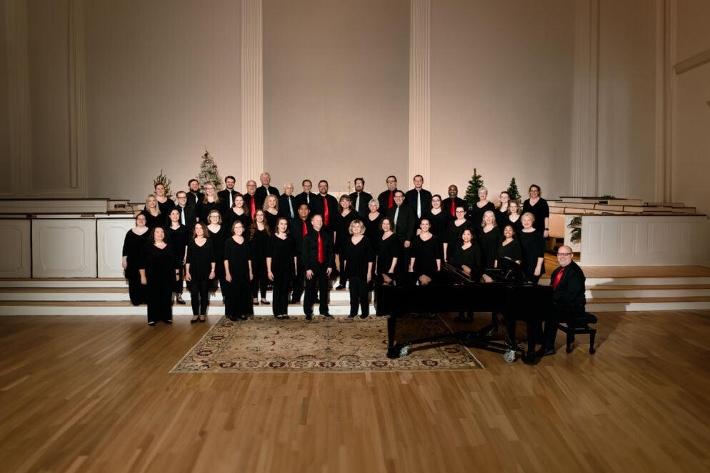 A group of choral members from the Choral Arts Society of Frederick stands indoors in black uniforms on wood floors. The multigenerational group is celebrating its 80th season.