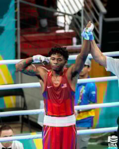 Jahmal Harvey wins a boxing match. The ref holds his hand up in the air.