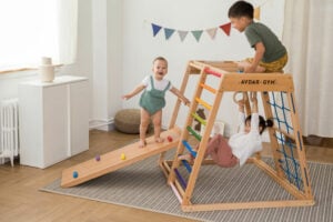 Children climb on a wooden playset with rainbow colored components.