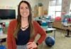 Casey Jeffers, a young woman smiles with her hand on her hip. She's in a classroom.