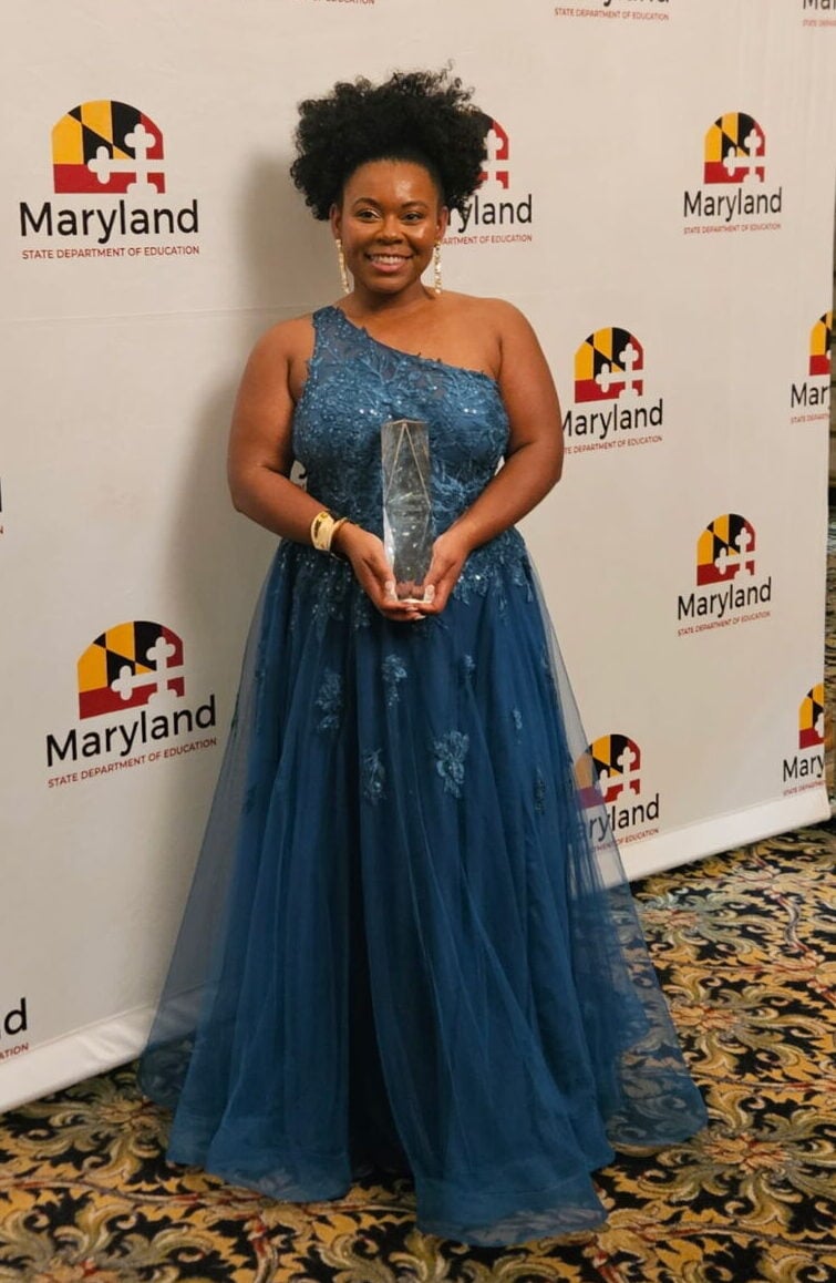 Woman in a blue dress holding a trophy