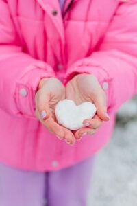 Child holding a heart made of snow