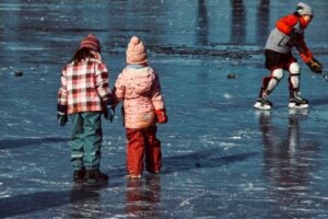 Three children ice skating on a lake