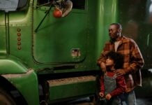 A child and adult looking at a large green truck