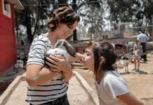 A mother and daughter at a petting zoo, the mother is holding a bunny