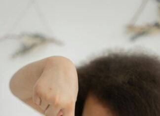 A child sticking her finger into a jar of clear slime