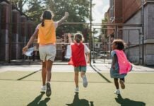 Three kids wearing capes run away from the camera
