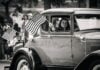 A girl holds an American flag out a car window at a Fourth of July parade