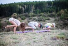 An adult woman and two children doing yoga outside