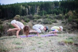 An adult woman and two children doing yoga outside