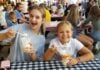 2026 Maryland State and County Fairs Two girls excitedly hold up spoons and their treats from the Maryland State fair at checkered picnic tables.
