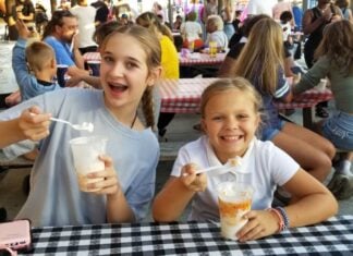 2026 Maryland State and County Fairs Two girls excitedly hold up spoons and their treats from the Maryland State fair at checkered picnic tables.