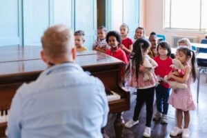 Man playing piano for a group of children