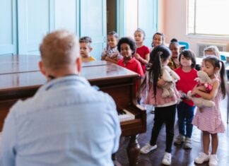 Man playing piano for a group of children