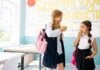 3 Simple Ways To Work Lifelong Healthy Habits Into Kids’ Routines Two girls enjoy an apple as healthy snack at school.