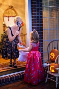 Young girl trick-or-treating at a woman's house