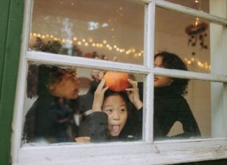 Soar Autism Center: Best Tips for an Autism-Friendly Halloween Three kids play by a window looking out on Halloween. One is holding a pumpkin and making a silly face.